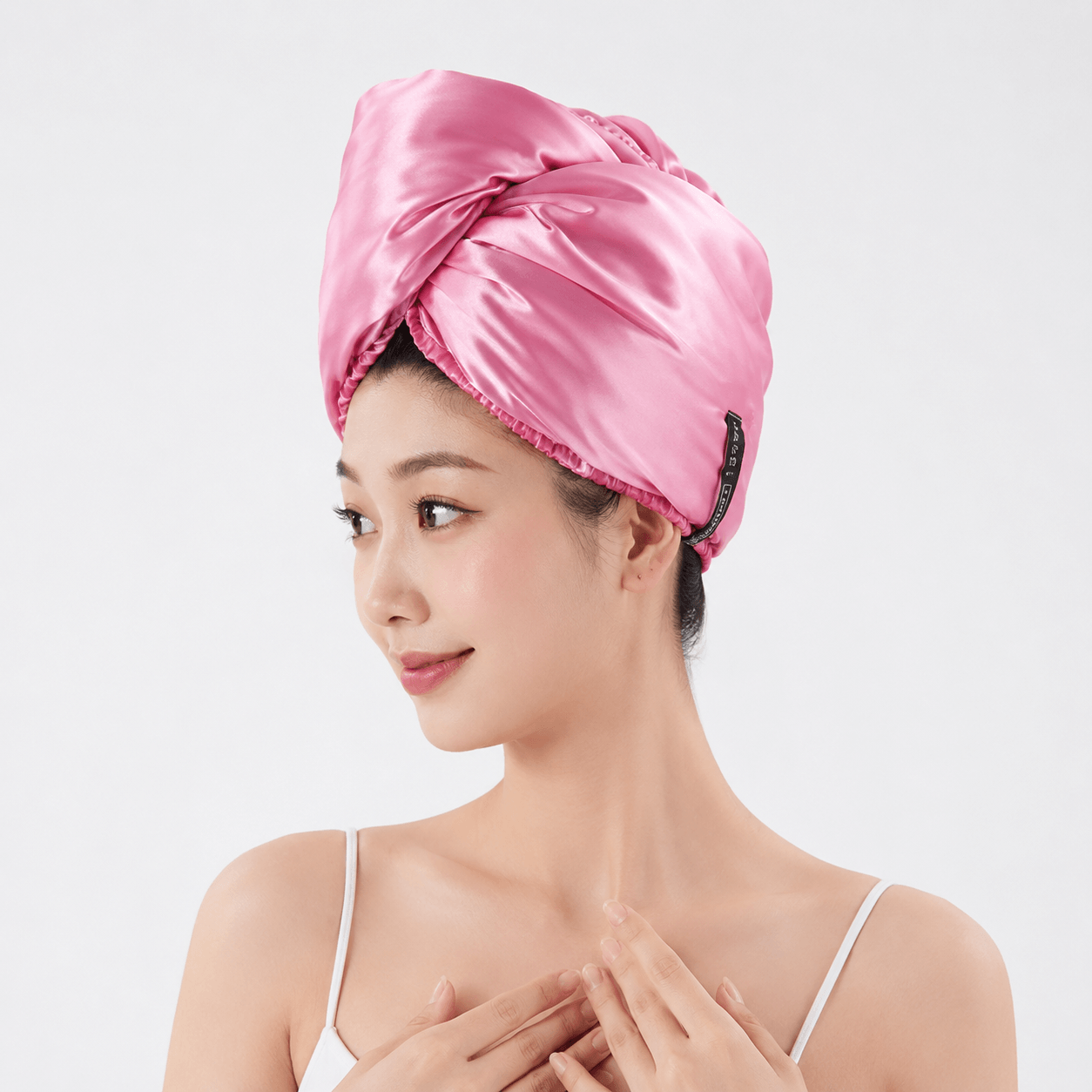 Aarniva satin microfiber hair drying turban in bright pink, stylishly worn by a woman post-shower for comfort and moisture management.