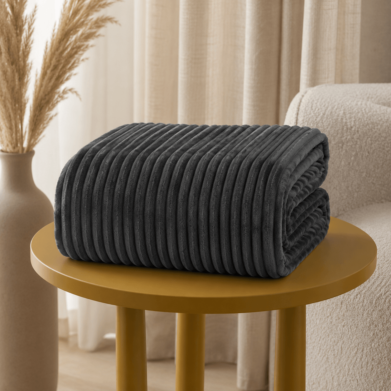 Aarniva Soft Flannel Throw Blanket with ribbed texture in dark charcoal on a gold table.