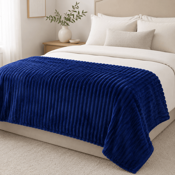 Aarniva ultra-soft flannel throw blanket with ribbed texture in royal blue, elegantly draped on a bed.