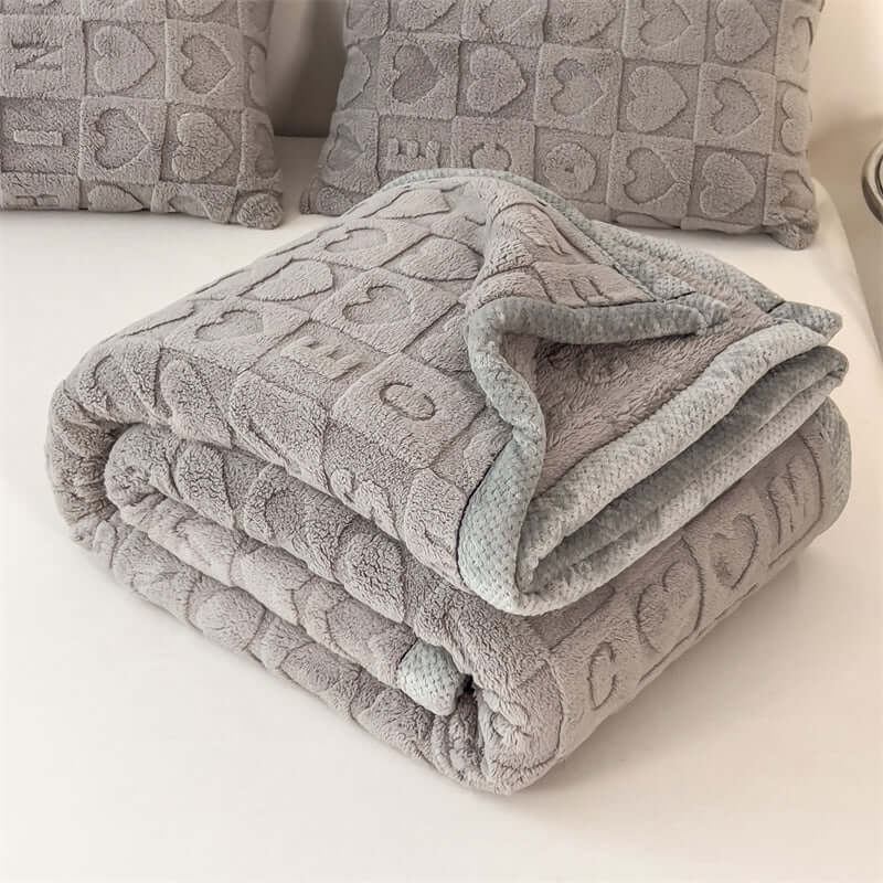 Multifunctional coral fleece blanket folded in gray, showcasing softness and elegance for home settings.